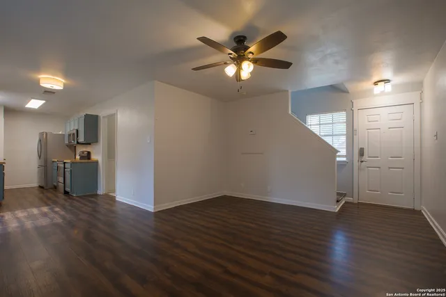 an empty room with wooden floor and a kitchen