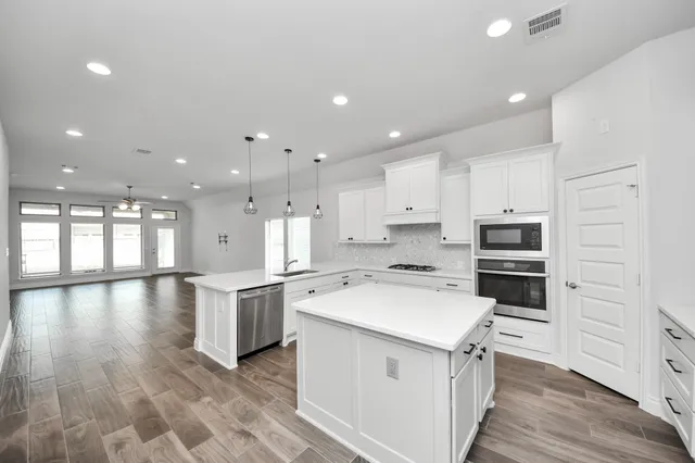 a kitchen with white cabinets and wooden floor