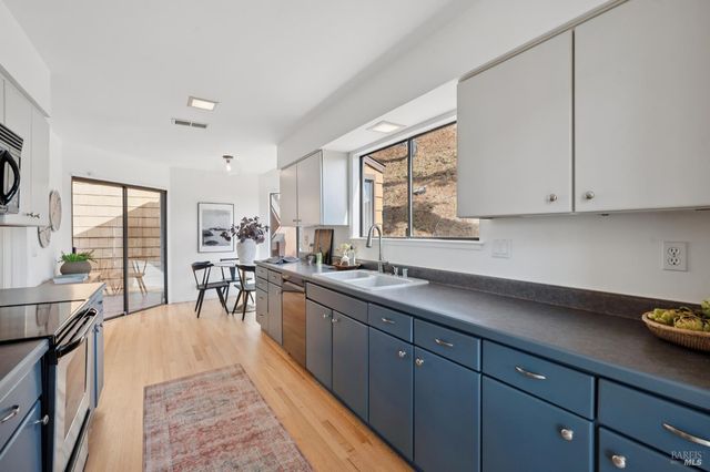 a open kitchen with stainless steel appliances granite countertop a refrigerator a sink dishwasher a stove and white countertops with wooden floor