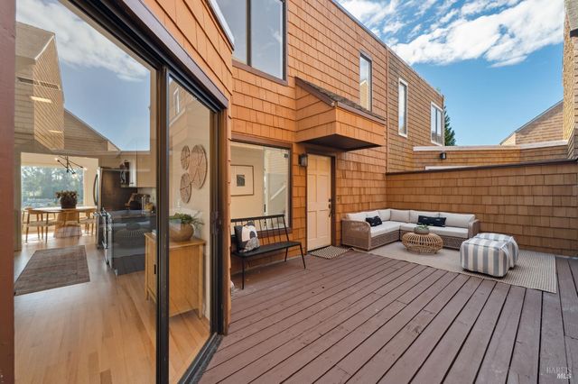 a view of a patio with a dining table and chairs with wooden floor and fence