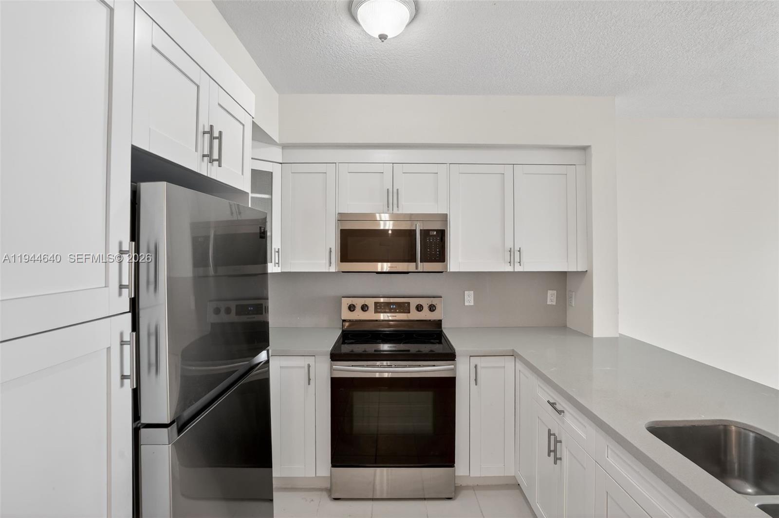 11060 Southwest 196th Street, Unit 605 Cutler Bay, FL 33157 - Photo 8 of 26 a kitchen with stainless steel appliances a stove a microwave and a refrigerator