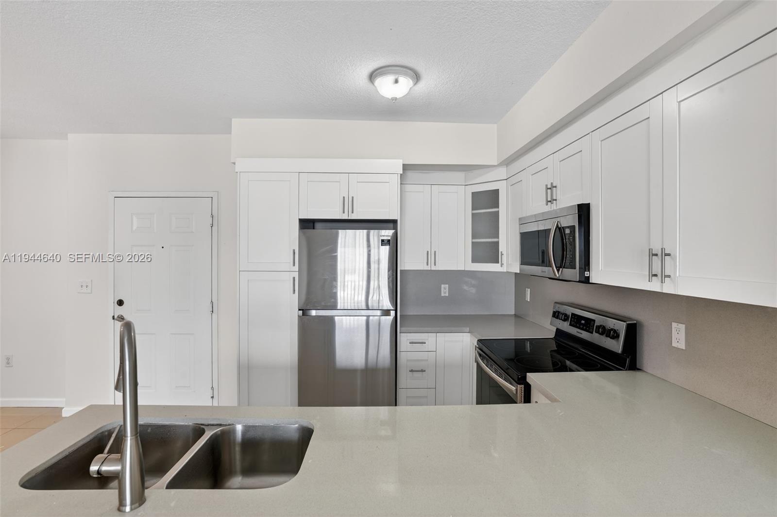 11060 Southwest 196th Street, Unit 605 Cutler Bay, FL 33157 - Photo 9 of 26 a kitchen with stainless steel appliances a sink and a refrigerator