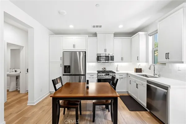 a kitchen with stainless steel appliances a table chairs microwave and cabinets