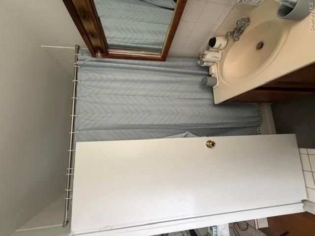 191 Birch Hill Road, Unit 3 Locust Valley, NY 11560 - Photo 10 of 15 Bathroom featuring classic white subway tile, pedestal sink with chrome fixtures, wood-framed mirror, and gray patterned shower curtain