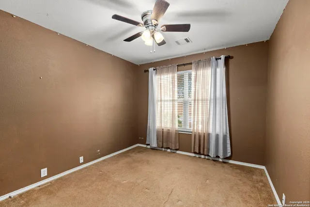 an empty room with windows and fan