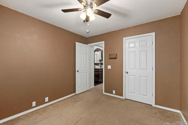an empty room with closet and a chandelier fan