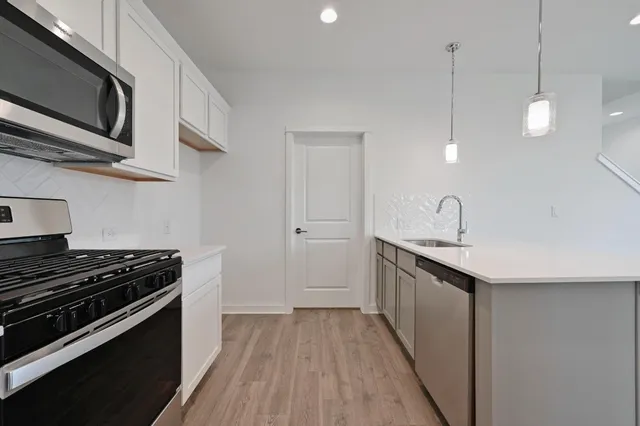 a kitchen with stainless steel appliances a stove sink microwave and cabinets