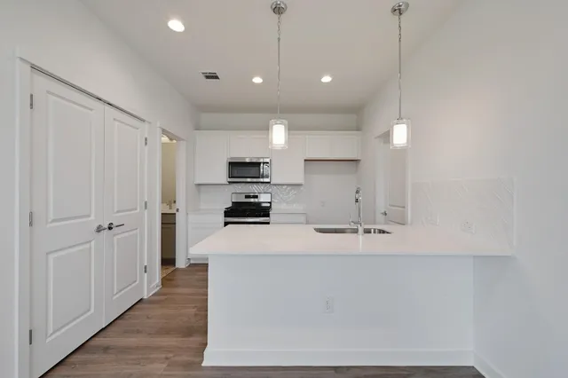 a large kitchen with stainless steel appliances a large counter top a sink a refrigerator and a window