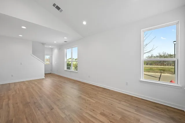 an empty room with wooden floor and windows