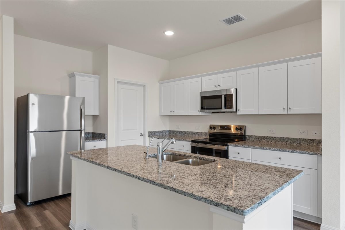 113 Rother Place Taylor, TX 76574 - Photo 12 of 34 Kitchen with appliances with stainless steel finishes, white cabinets, dark stone counters, dark wood-style flooring, and recessed lighting