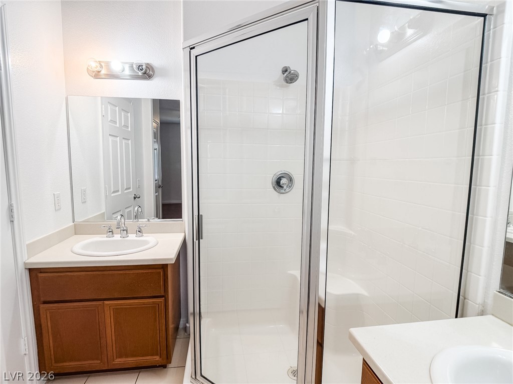 7701 West Robindale Road, Unit 110 Las Vegas, NV 89113 - Photo 11 of 21 Well-lit bathroom with a glass-enclosed shower and a vanity with ample counter space.