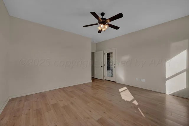 an empty room with wooden floor and a ceiling fan
