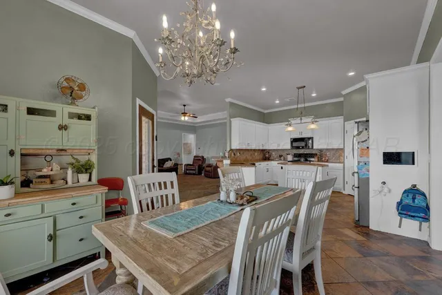 a view of a dining room and livingroom with furniture a chandelier and kitchen view
