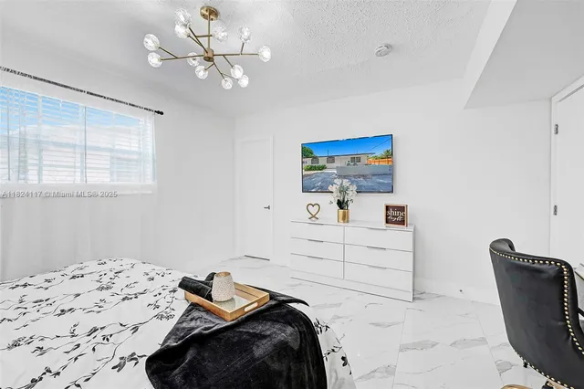 a bedroom with a bed and a chair with the view of bathroom