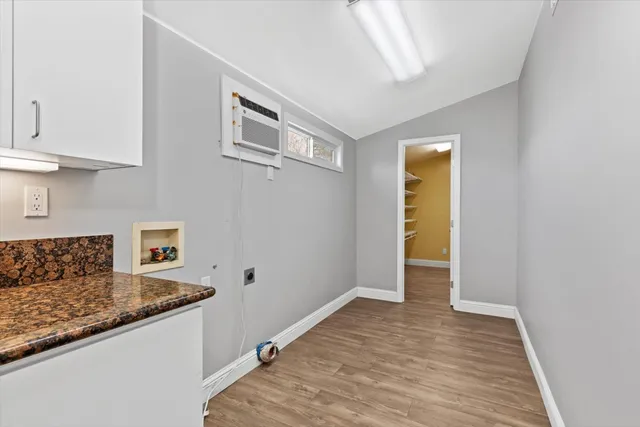 a view of an empty room with wooden floor and windows