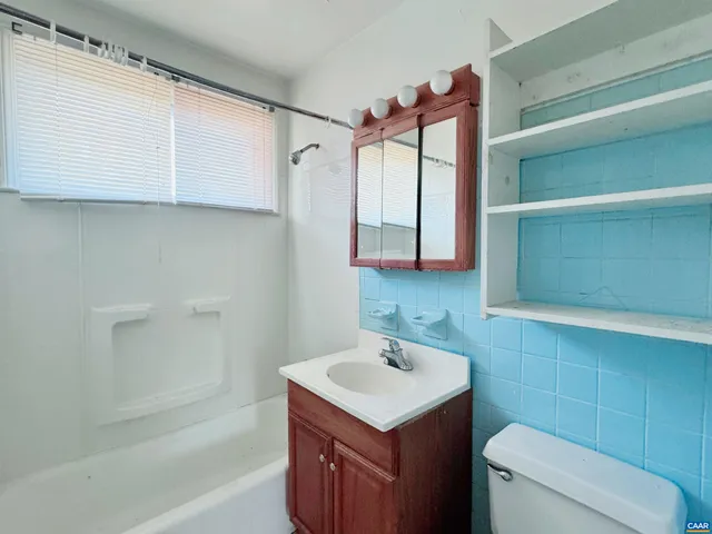 a bathroom with a sink toilet vanity and tub