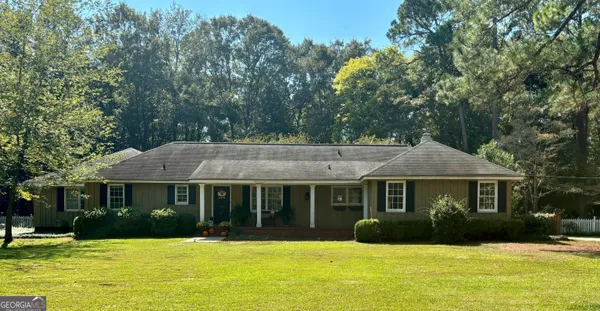 a view of a house with a yard plants and large tree
