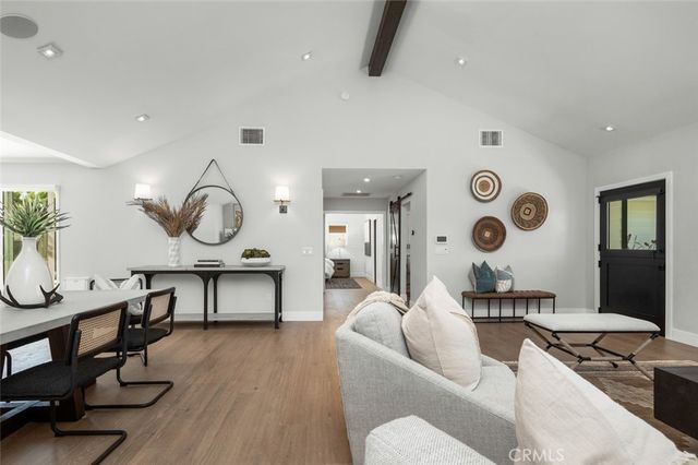 a living room with furniture kitchen view and a wooden floor
