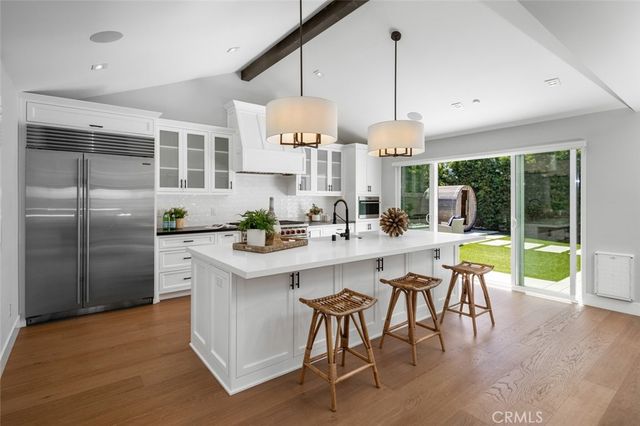 a kitchen with a dining table chairs sink and white cabinets