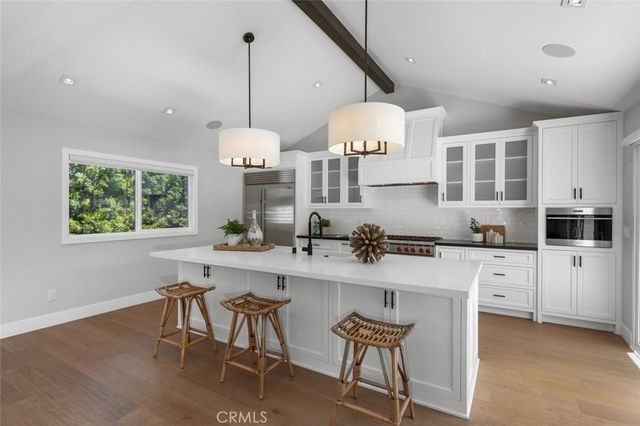 a kitchen with kitchen island granite countertop a sink a center island a stove and a window