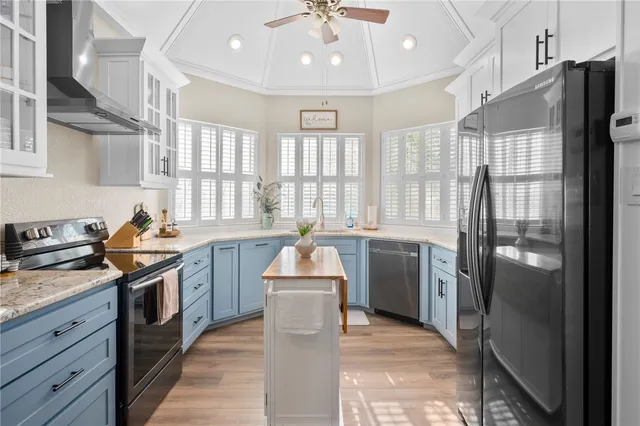 a kitchen with stainless steel appliances granite countertop a stove a sink dishwasher and white cabinets with wooden floor