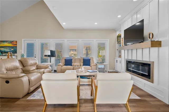 a living room with furniture kitchen view and a wooden floor