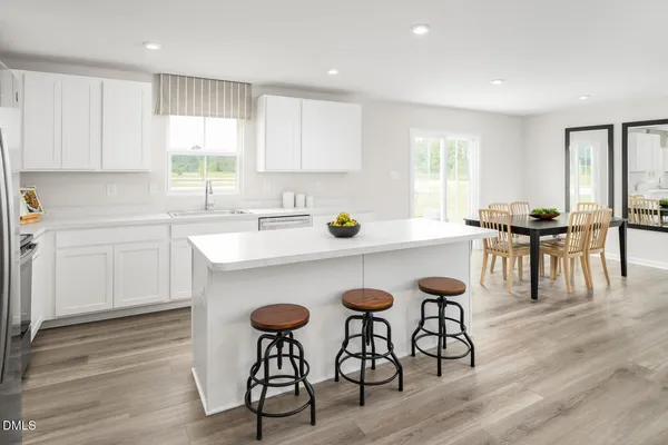 a kitchen with stainless steel appliances granite countertop a sink a stove a kitchen island with chairs and white cabinets