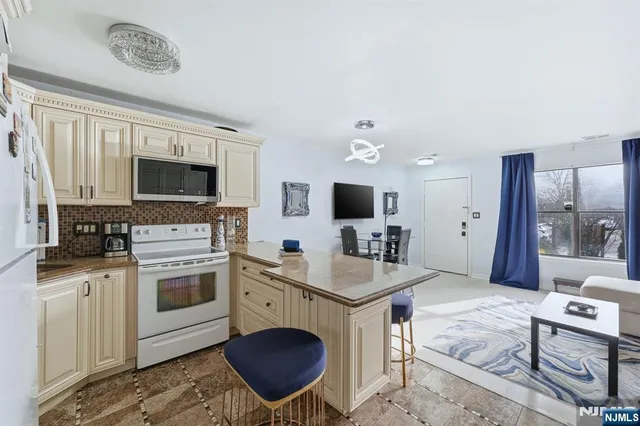 a living room with stainless steel appliances furniture a fireplace and a flat screen tv
