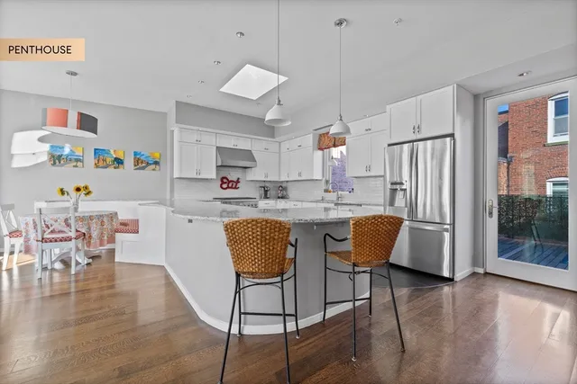 a kitchen with stainless steel appliances granite countertop a refrigerator a sink dishwasher a dining table and chairs with wooden floor