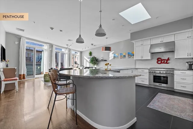 a kitchen with stainless steel appliances granite countertop a sink a stove a dining table and chairs