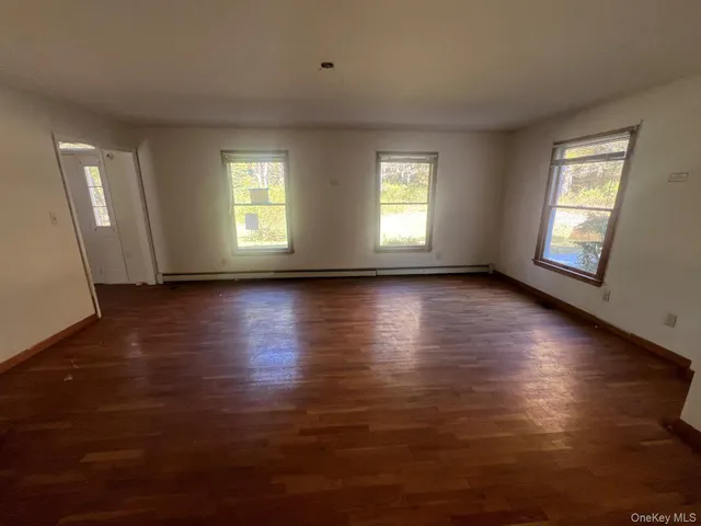 a view of an empty room with wooden floor and window