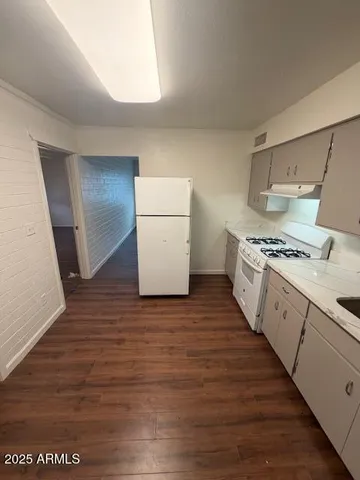 a kitchen with cabinets wooden floor and stainless steel appliances