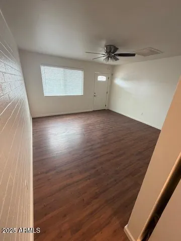 an empty room with wooden floor fan and windows
