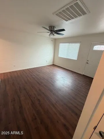 en empty room with wooden floor ceiling fan and windows