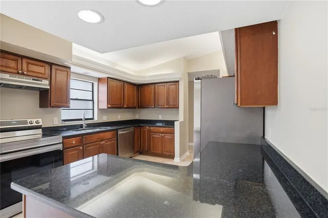 a kitchen with stainless steel appliances granite countertop a sink stove and cabinets