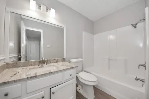 a bathroom with a granite countertop sink a toilet and shower