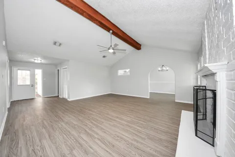 a view of empty room with wooden floor and kitchen