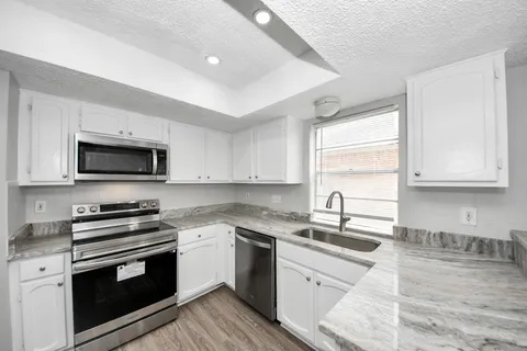 a kitchen with stainless steel appliances a sink dishwasher a stove and a microwave oven with cabinets