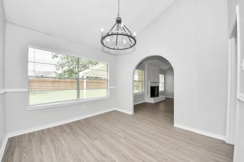 an view of an empty room with wooden floor and window