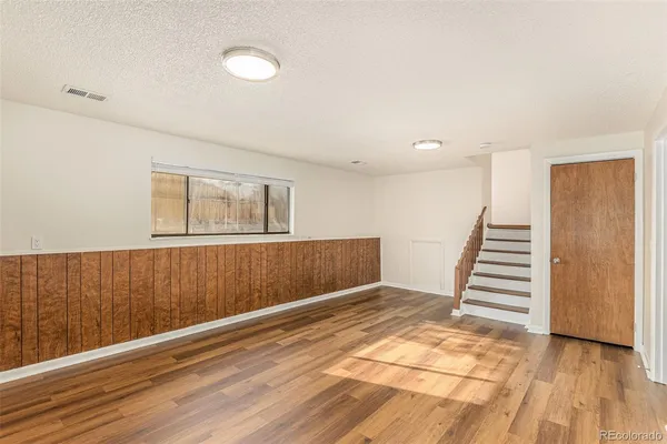 a view of an empty room with wooden floor and stairs