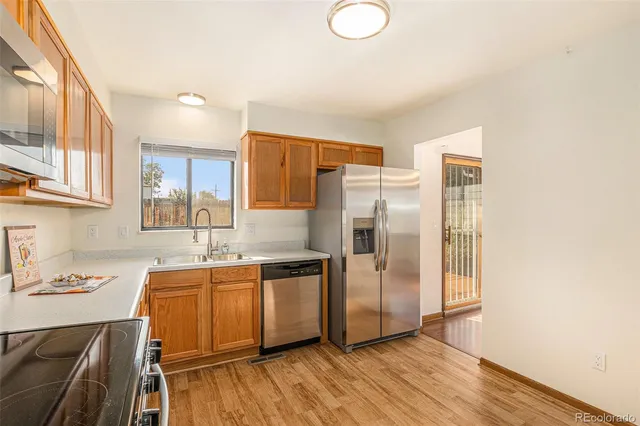 a kitchen with stainless steel appliances a sink cabinets and wooden floor