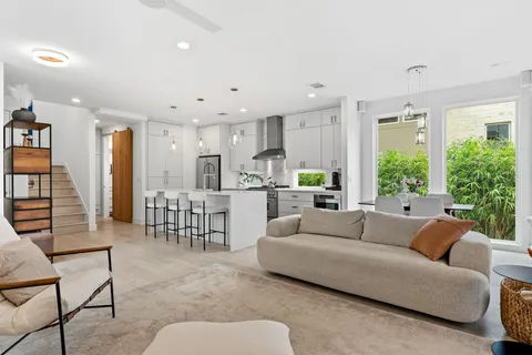 a living room with furniture next to a large window with garden view