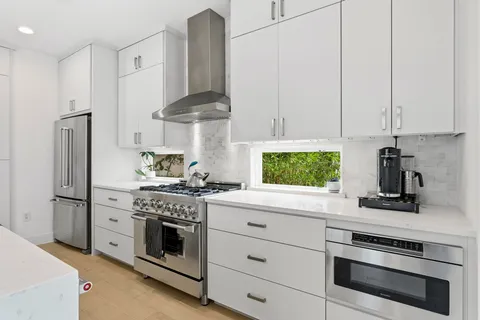a kitchen with stainless steel appliances white cabinets and a stove top oven
