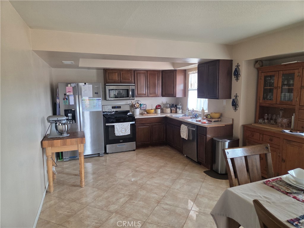 13955 Iroquois Road Apple Valley, CA 92307 - Photo 6 of 19 a kitchen with stainless steel appliances a stove a sink a refrigerator and cabinets
