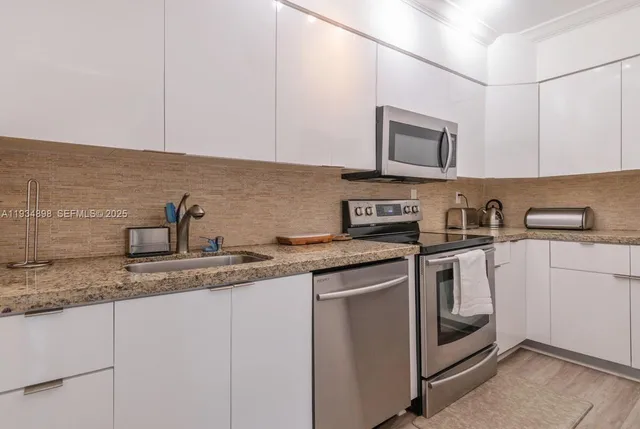 a kitchen with stainless steel appliances granite countertop white cabinets a sink and dishwasher