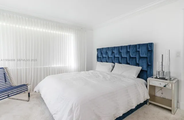 a bed sitting in a bedroom next to a window and a lamp