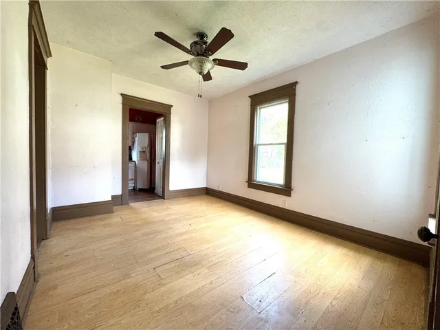 an empty room with a window and ceiling fan