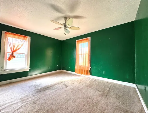 a view of an empty room with a window and a ceiling fan