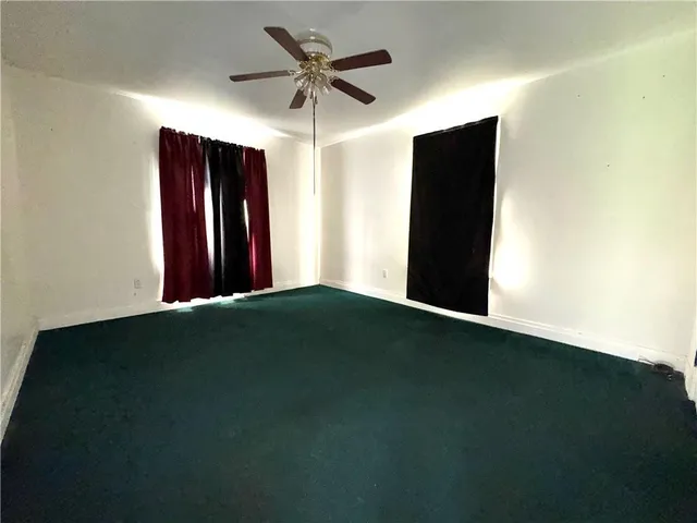 a view of an empty room with a ceiling fan and a window
