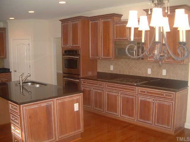 2916 Elmfield Street Raleigh, NC 27614 - Photo 2 of 10 The Bright and open eat-in Kitchen features SS appliances, upgraded custom Cabinetry w/roll out shelves in all the lower cabinets, Tile back splash, amazing level 5 black galaxy granite countertops and a breakfast bar at the center island.